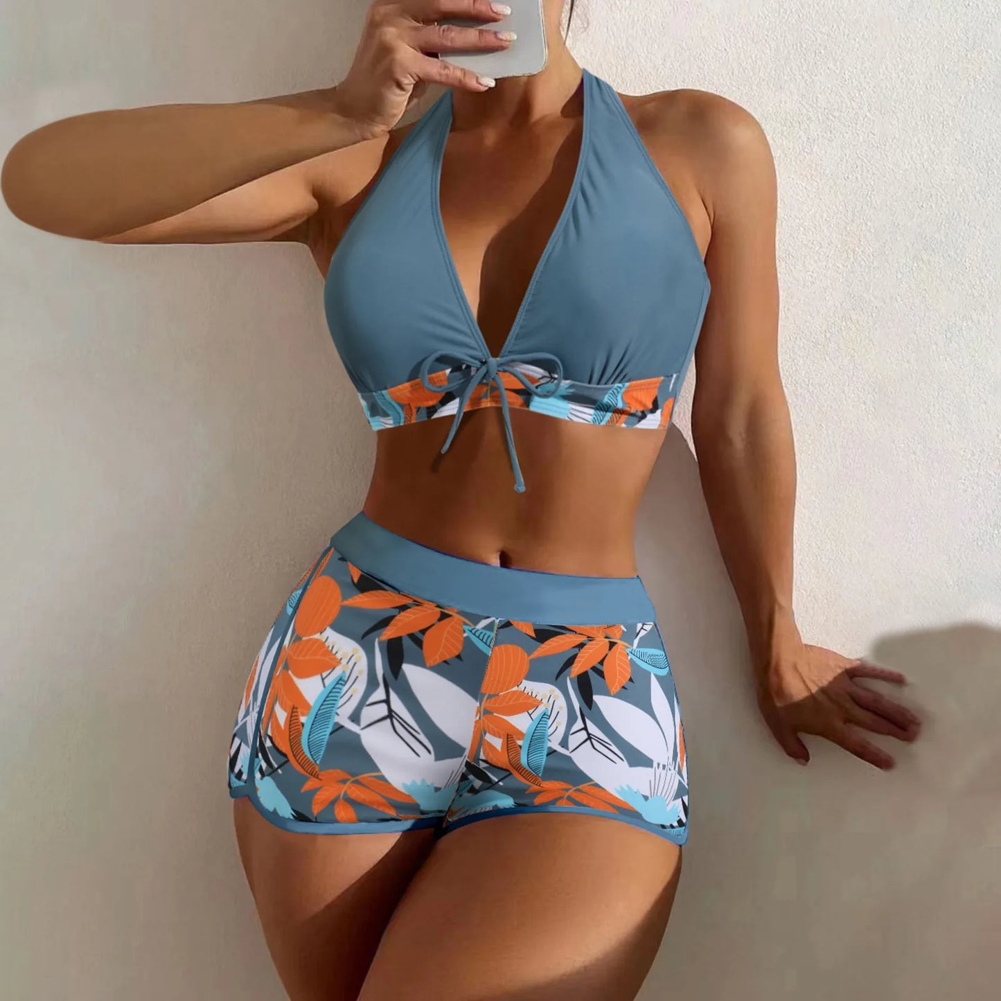 Woman wearing a blue bikini with floral patterns against a neutral background