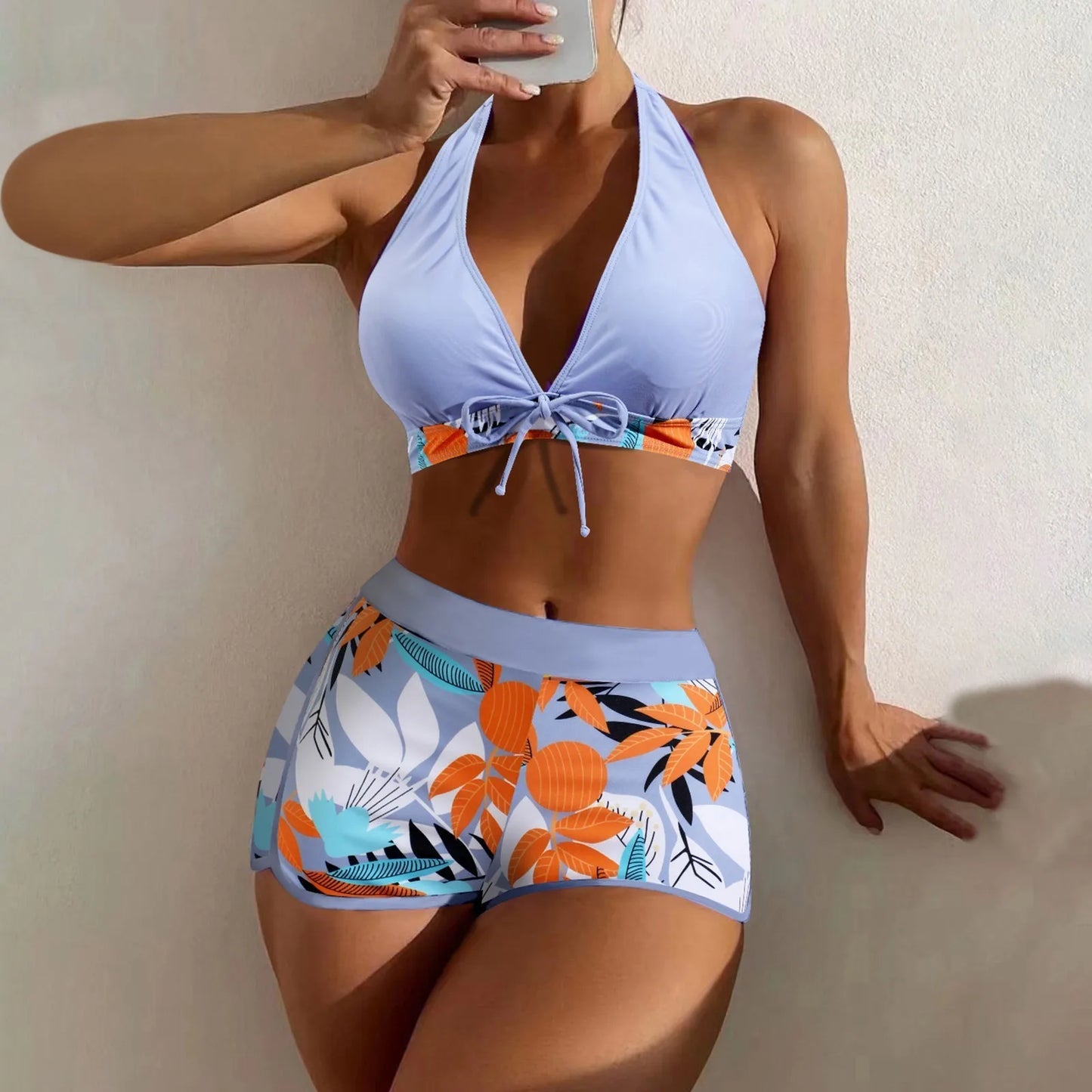 Woman wearing a colorful bikini with a floral pattern against a neutral background