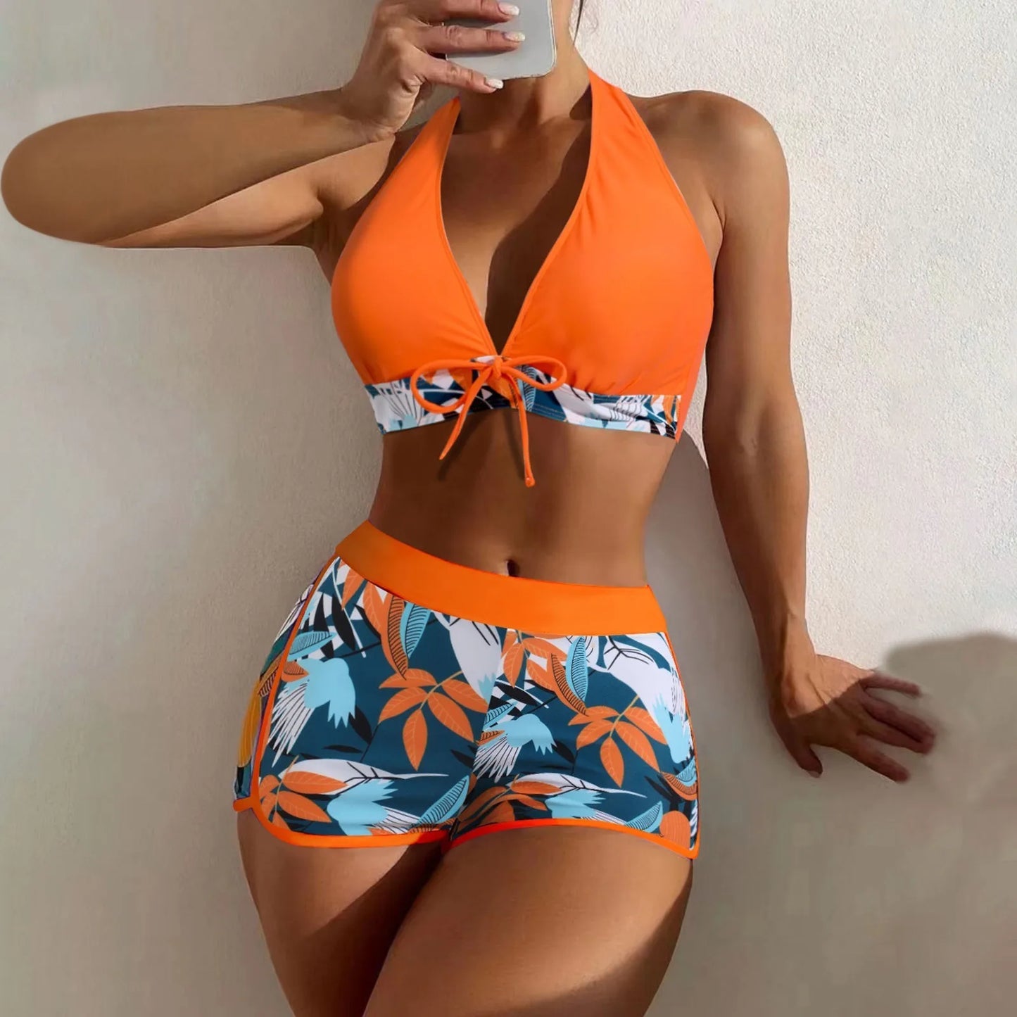 Orange and blue floral bikini set worn by a person against a neutral background