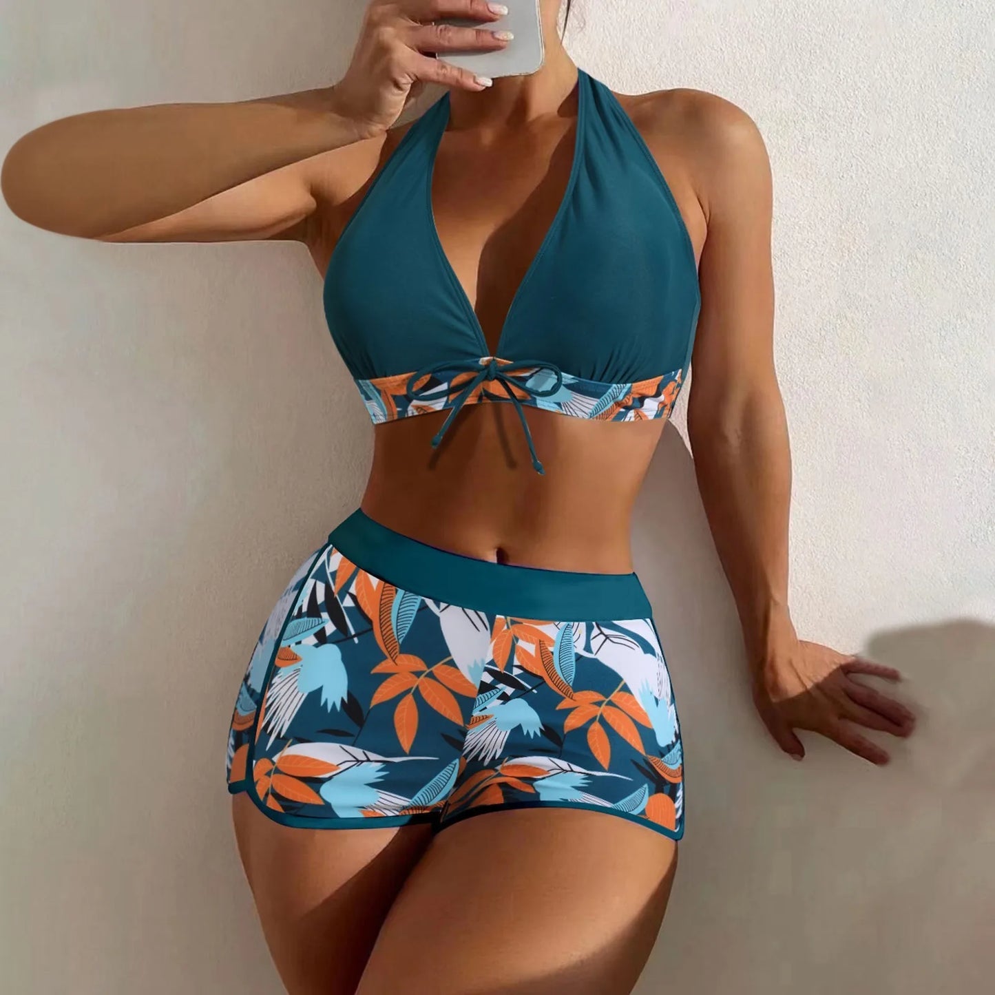 Woman wearing a blue and orange floral bikini against a plain background