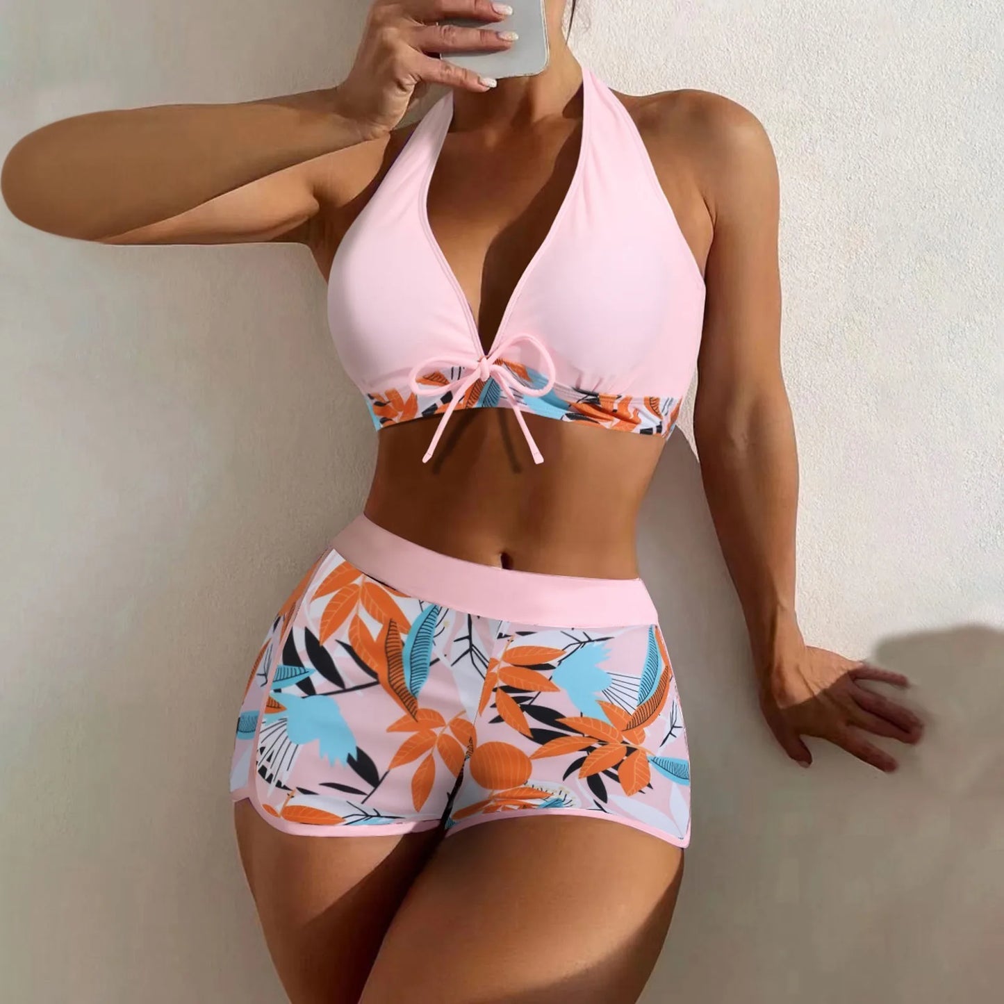 Bikini set with pink top and colorful floral shorts against a neutral background