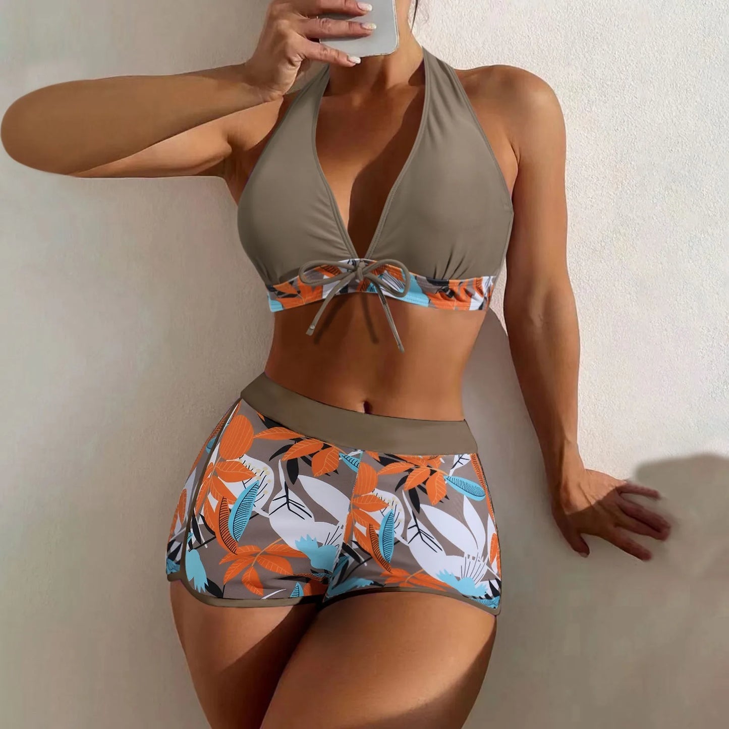 Woman wearing a two-piece swimsuit with floral pattern against a neutral background