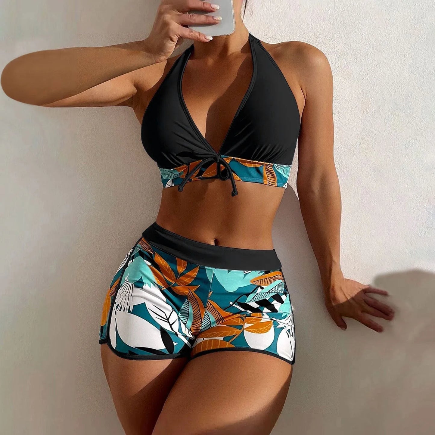 Woman wearing a black and colorful bikini against a neutral background