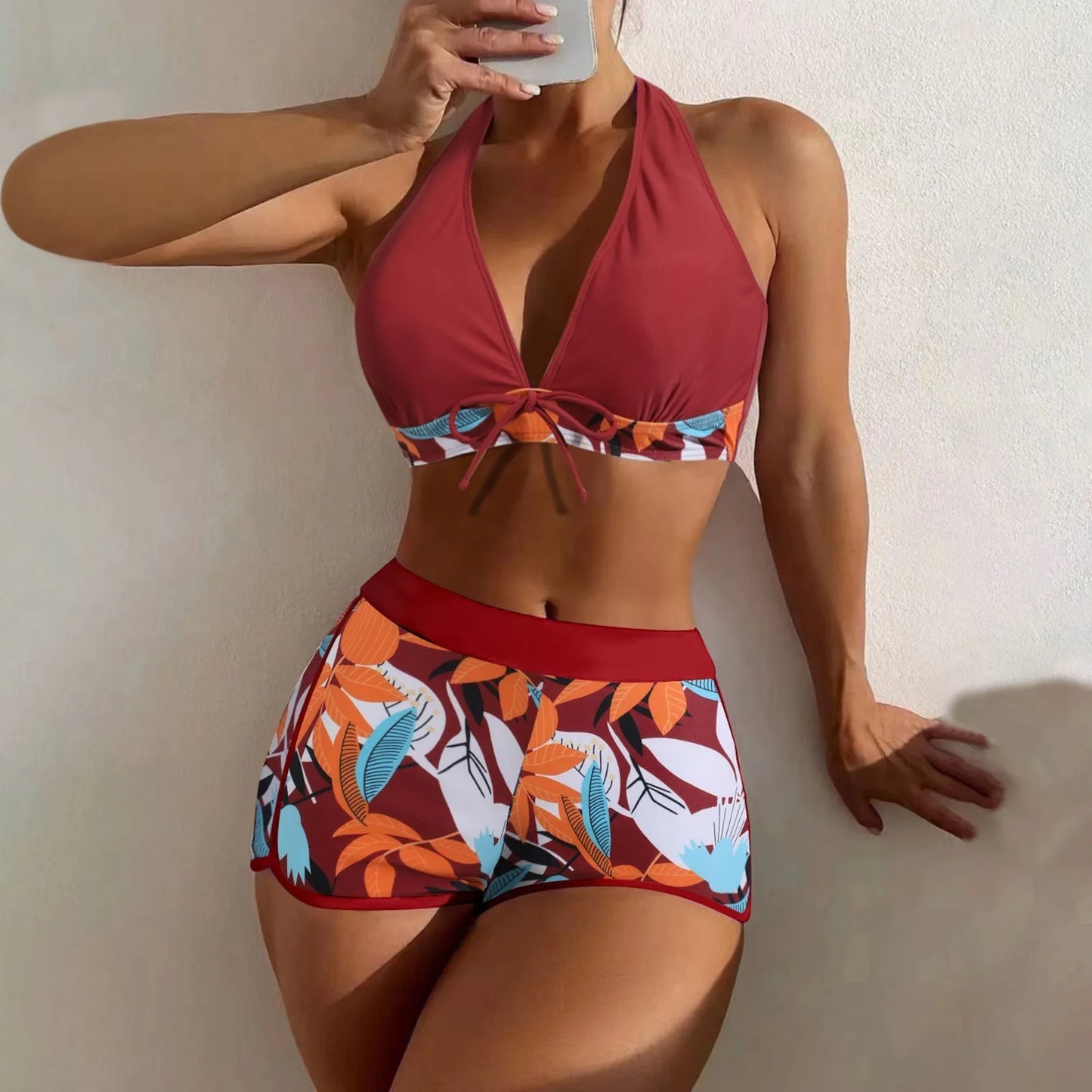 Red bikini with floral pattern worn by a person against a neutral background