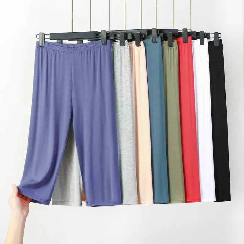 Hanging pants in various colors on a rack against a white background
