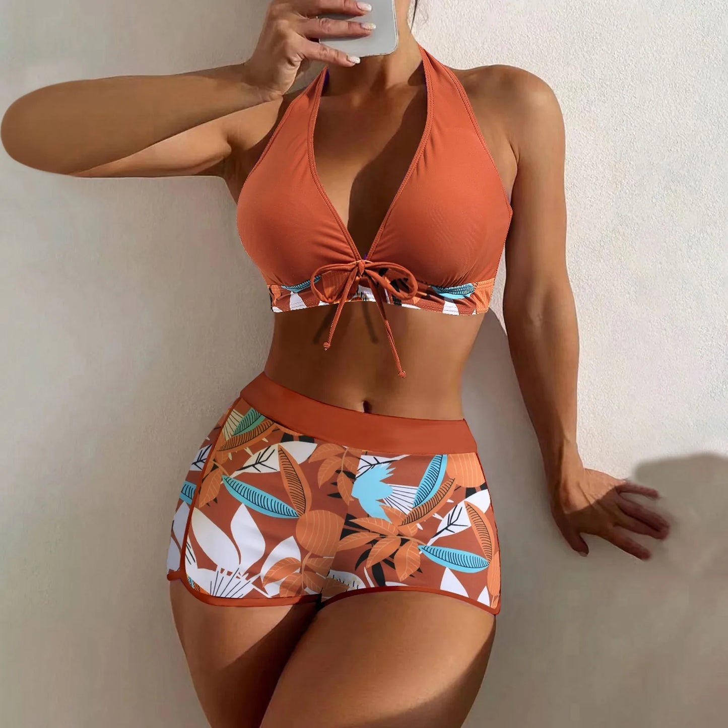 Person wearing an orange bikini with floral patterns against a plain background