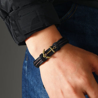 A man showcases a black leather bracelet adorned with an anchor, emphasizing a nautical theme in his accessory choice.