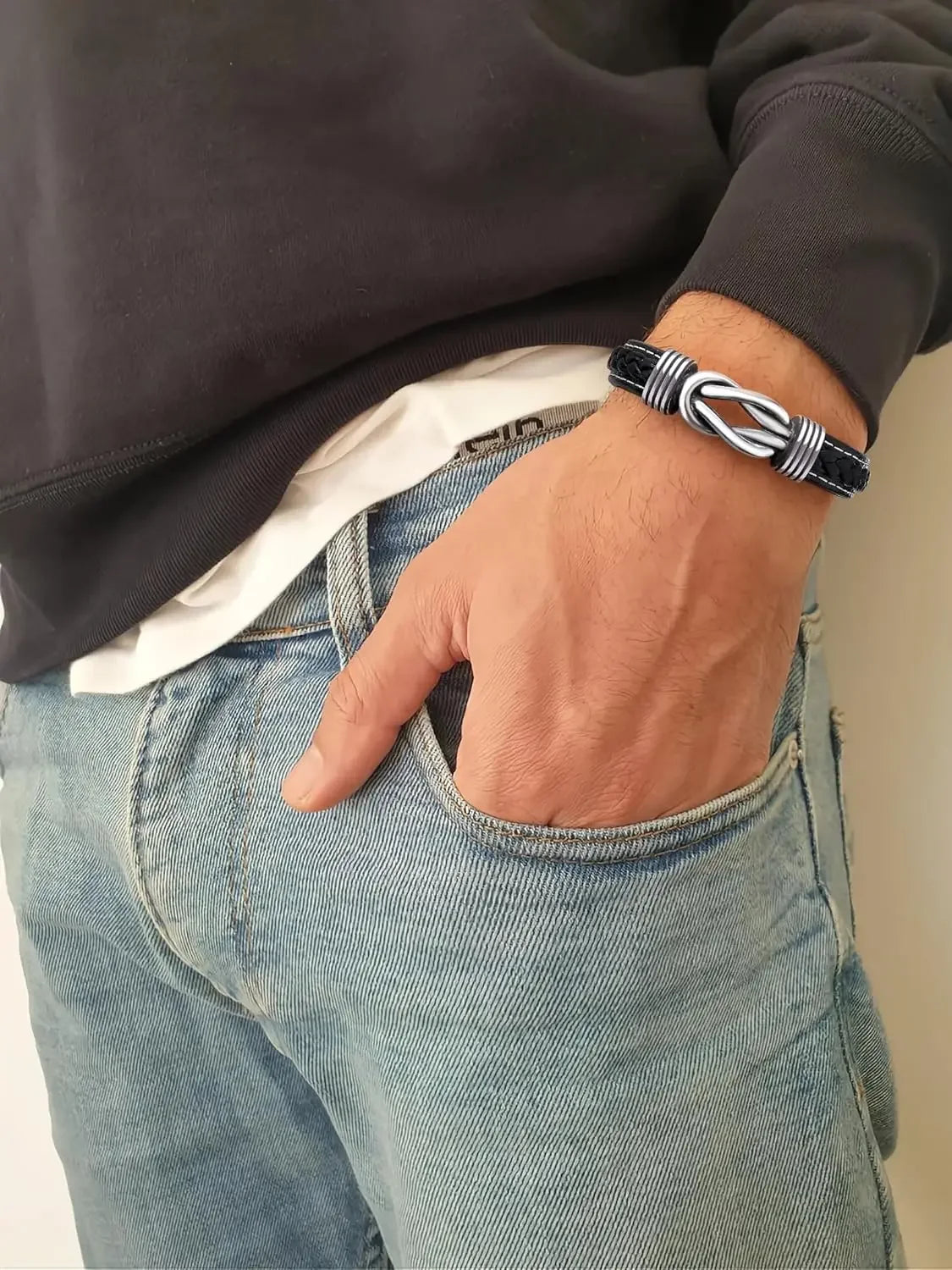 A man displays a silver bracelet complemented by a black leather band, highlighting a modern accessory choice.