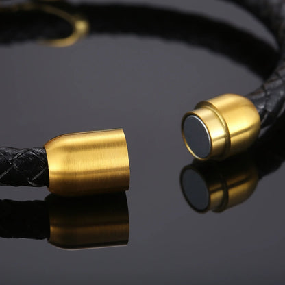 A gold-plated bullet button adorns a sleek black leather bracelet, showcasing a blend of elegance and rugged style