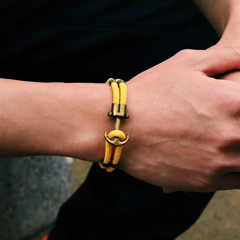 A man showcases a stylish yellow bracelet featuring a sleek gold clasp on his wrist.