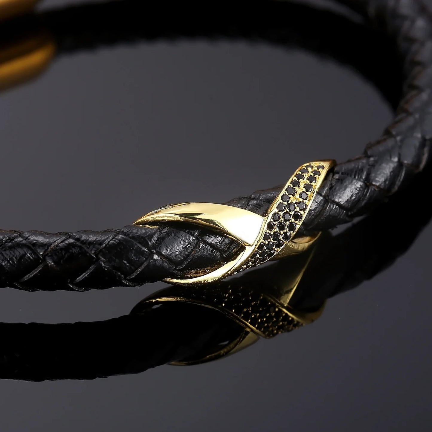 A black leather bracelet featuring an infinity knot design and a gold-plated clasp, showcasing elegance and style