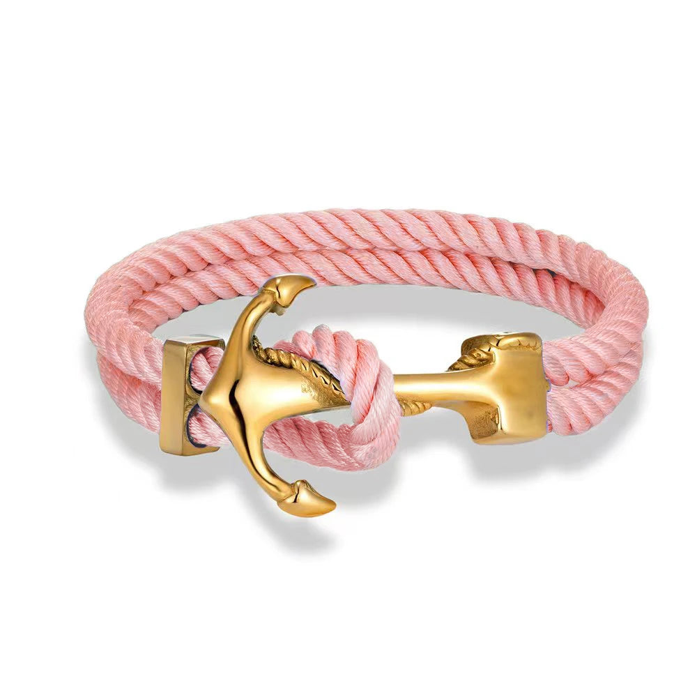 A pink rope bracelet featuring a gold anchor charm, elegantly combining nautical style with a vibrant color.