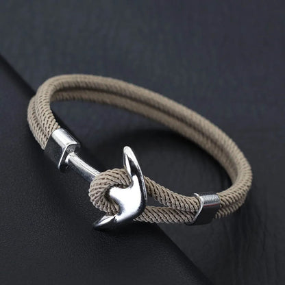 A stylish beige rope bracelet featuring a sleek silver anchor charm, perfect for nautical-themed accessories.