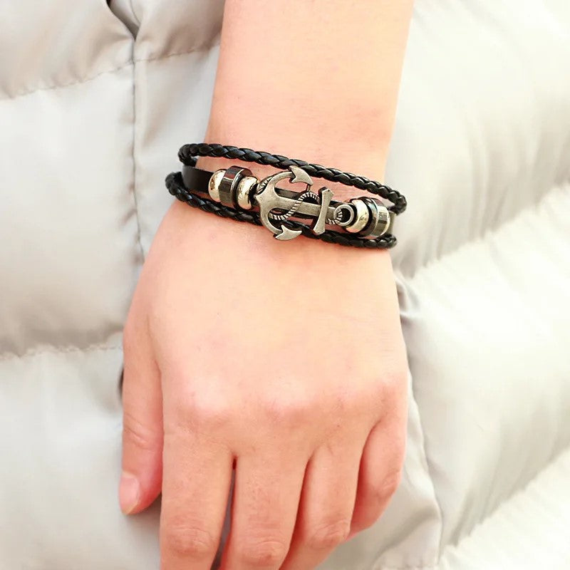 . Close-up of a woman’s wrist featuring a chic black leather bracelet with a prominent anchor design, symbolizing strength and adventure.