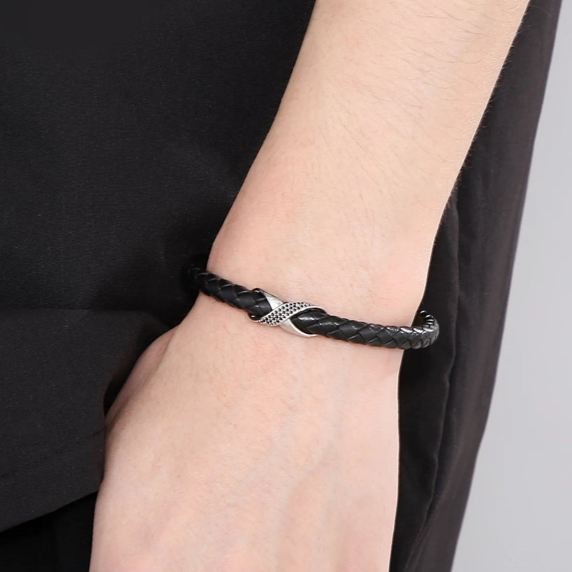 A black leather bracelet featuring a silver cross, elegantly combining style and faith in a simple yet striking design