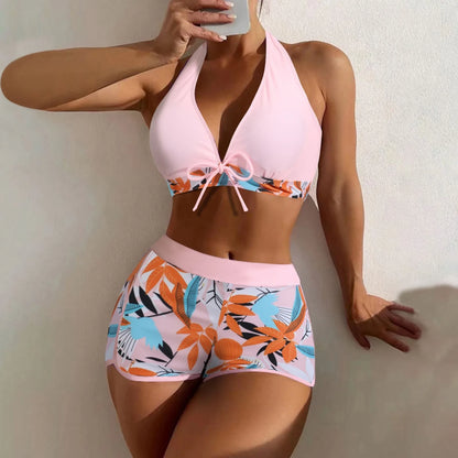 Bikini set with pink top and colorful floral shorts against a neutral background