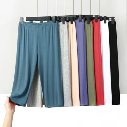 Hanging pants in various colors on a rack against a white wall.