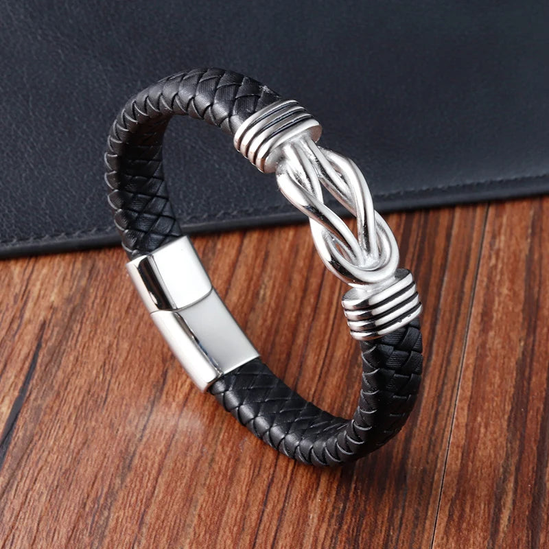 A black leather bracelet featuring a sleek black metal clasp, showcasing a modern and stylish design.