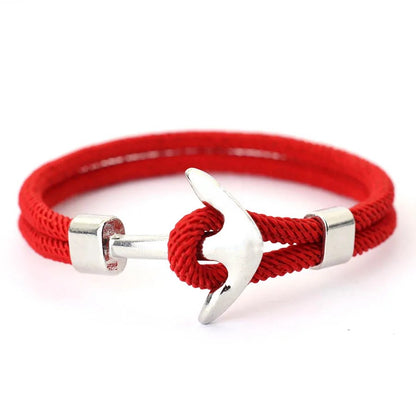 A vibrant red rope bracelet adorned with a polished silver anchor, blending fashion with a maritime touch.