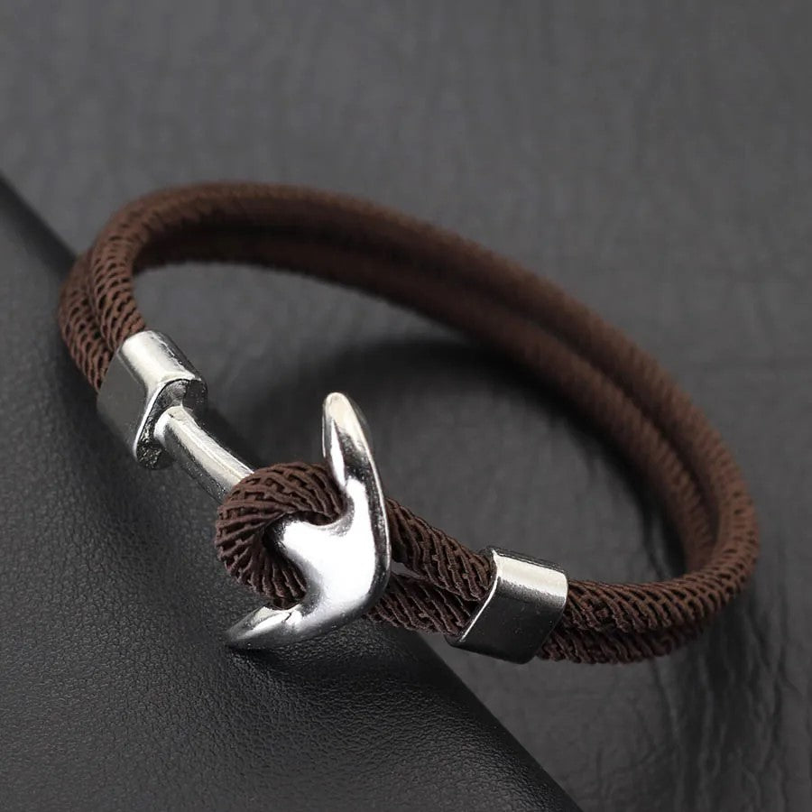 A stylish brown rope bracelet featuring a sleek silver anchor charm, perfect for nautical-themed accessories.