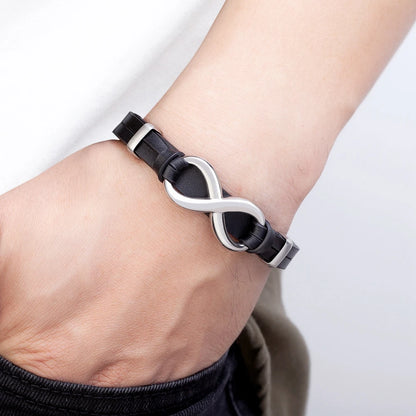 A man showcases a black leather bracelet adorned with an infinity symbol, symbolizing endless possibilities and connections.